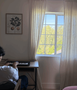 man playing piano with orchard view out window